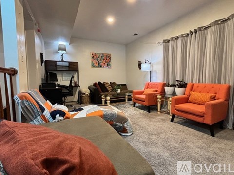 A living room with a grey carpet and orange chairs.