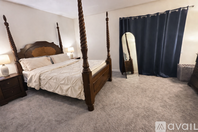 A bedroom with a four poster bed and a surfboard leaning against the wall.