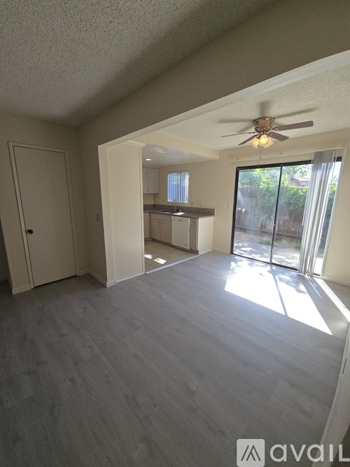 A room with a ceiling fan and sliding glass doors leading to a balcony.