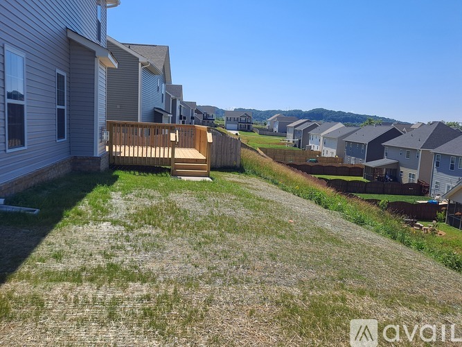 A grassy area in front of a house with a wooden deck.