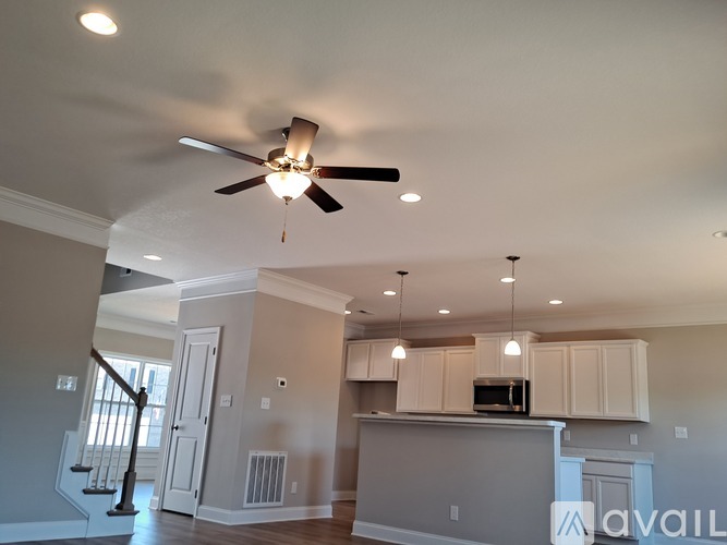 A spacious living room with a ceiling fan and light fixture.