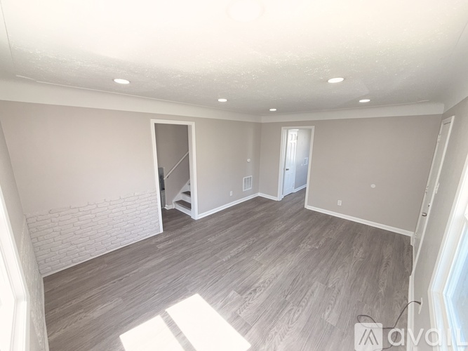 A spacious room with wooden flooring and white walls.
