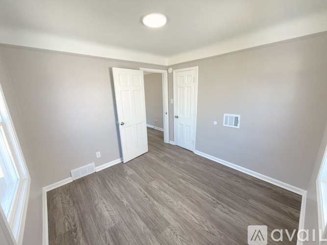 A room with wood flooring and two white doors.