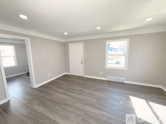 A spacious room with light grey walls and a wooden floor.