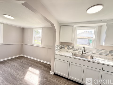 A kitchen with white cabinets and a large window.