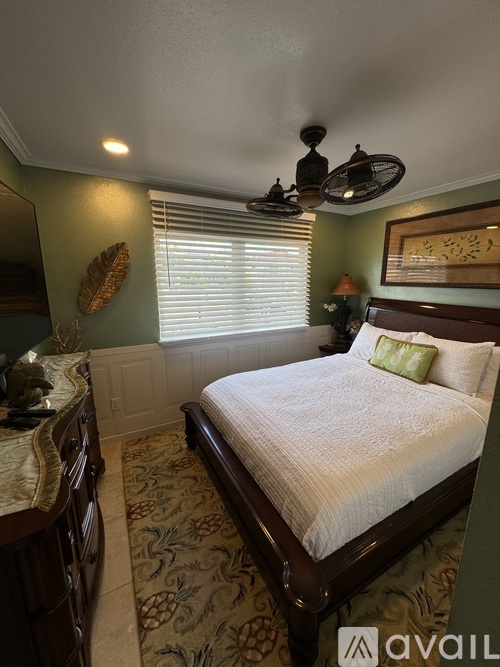 A bedroom with a bed, dresser, and a ceiling fan.