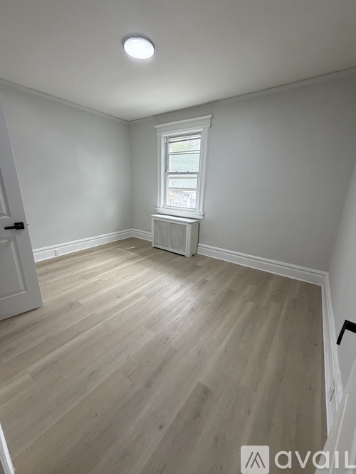 A room with light wood flooring and a window with white trim.