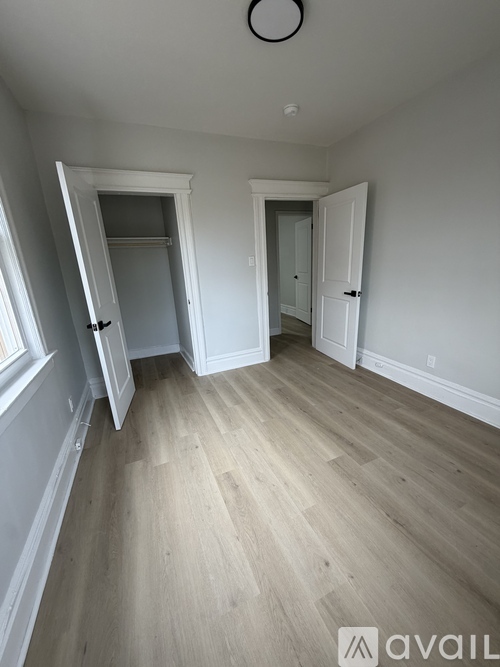 A room with wooden flooring and two doors.