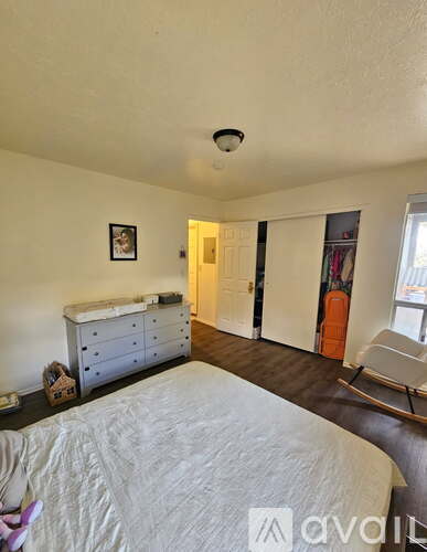 A bedroom with a white bed and a dresser with a baby's crib on top.