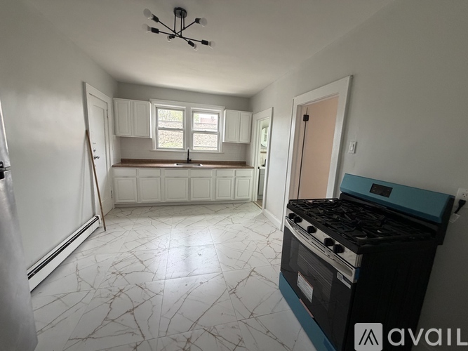 A kitchen with a black stove top oven and a white marble floor.