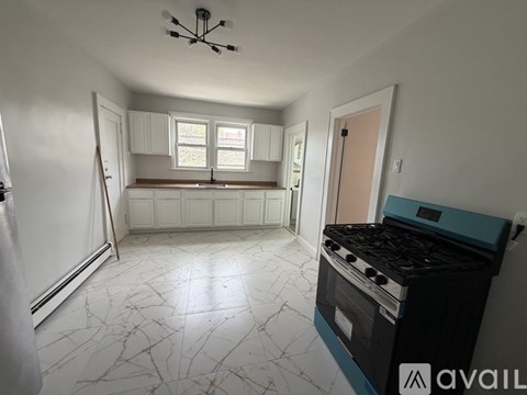 A kitchen with a black stove top oven and a white marble floor.