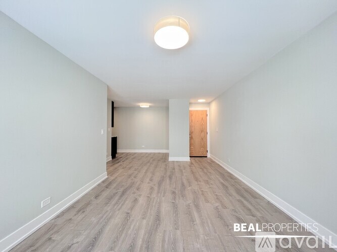 A spacious room with a light on the ceiling and a door at the end.