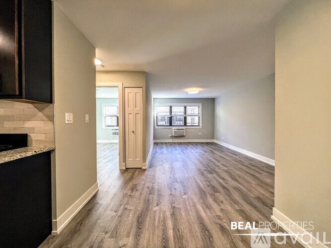 A spacious room with wooden flooring and a large window.