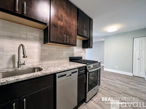 A modern kitchen with dark wood cabinets and stainless steel appliances.