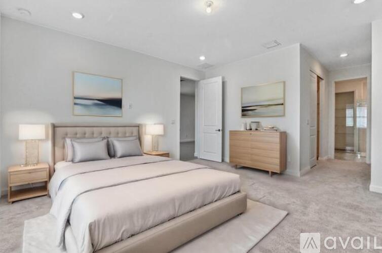 A bedroom with a large bed and a painting on the wall.