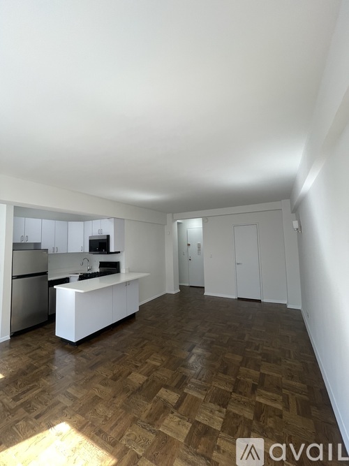 A kitchen with wooden flooring and white cabinets.