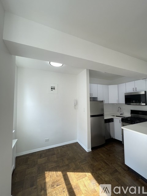 A kitchen with white cabinets and a wooden floor.