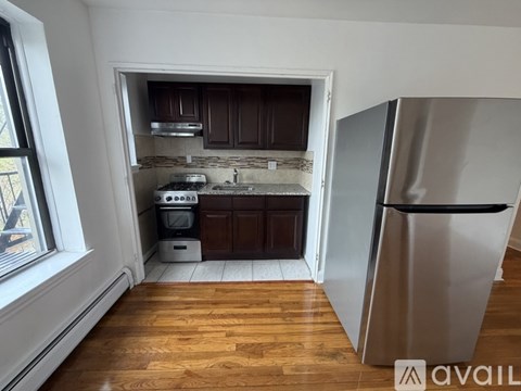 A kitchen with a stainless steel refrigerator and wooden floors.