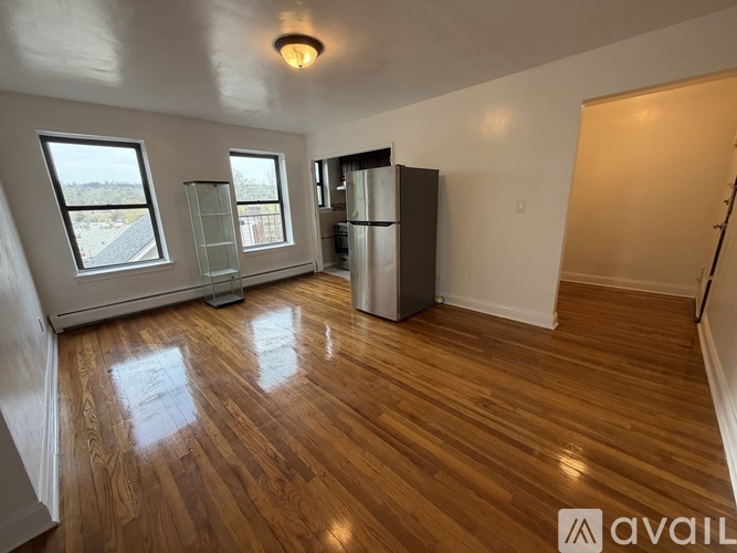 A room with wooden flooring and a refrigerator in it.