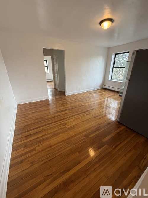 A room with wooden flooring and a refrigerator in the corner.
