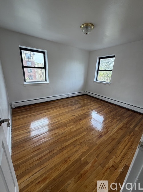 A room with wooden floors and two windows.