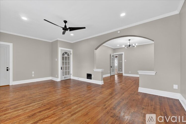 A spacious room with wood flooring and a ceiling fan.