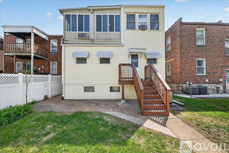 A two-story house with a white exterior and a wooden staircase leading to the second floor.