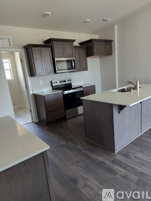 A kitchen with a white countertop and dark brown cabinets.