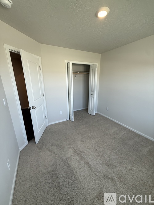 A spacious room with wooden floors and three windows.