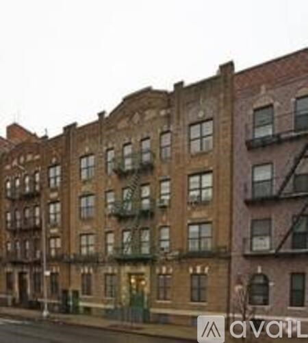 A row of brown brick buildings with green fire escapes.