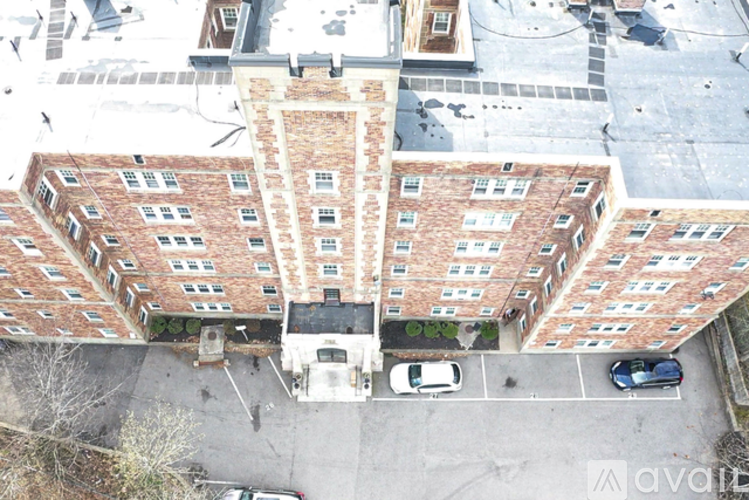 An aerial view of a red brick building with a parking lot in front.