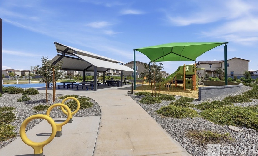 A park with a walkway, yellow rings, and a green canopy.