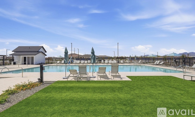 A pool area with a small building and lawn chairs.