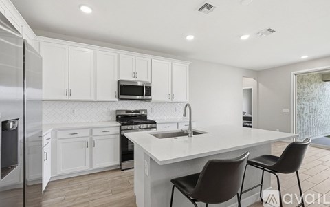 A kitchen with white cabinets and a black countertop.