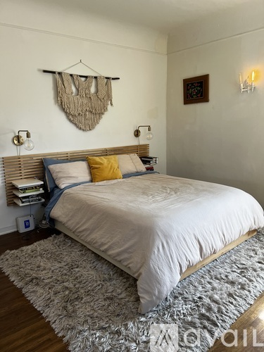 A bedroom with a large bed and a rug on the floor.