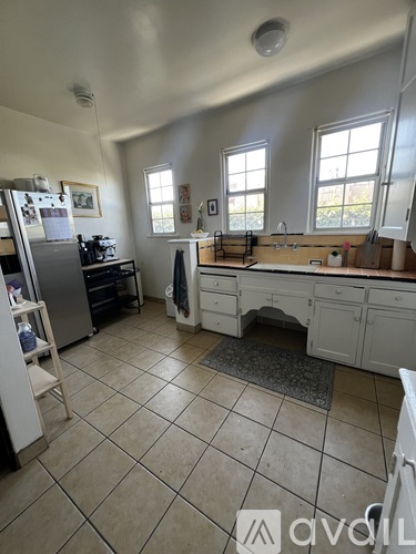 A kitchen with white cabinets and a tile floor.