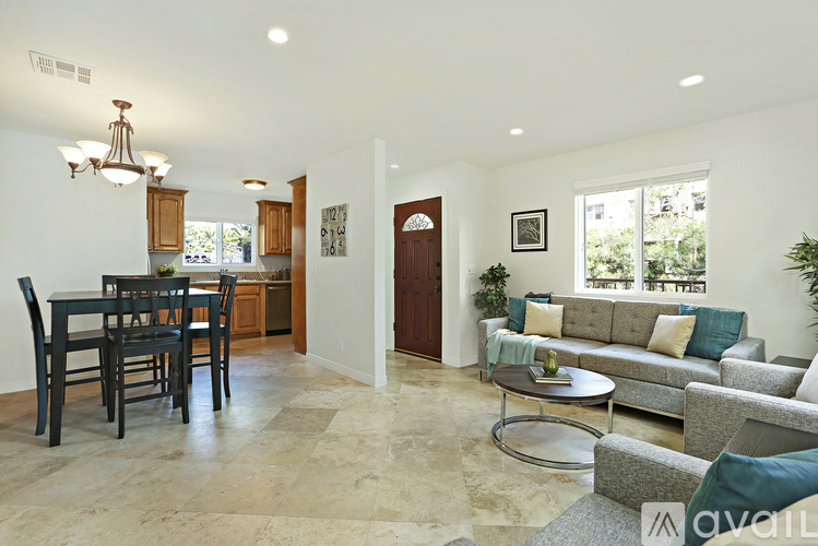 A living room with a grey couch and a dining table with chairs.