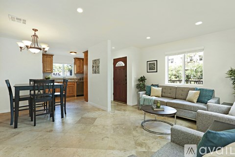A living room with a grey couch and a dining table with chairs.
