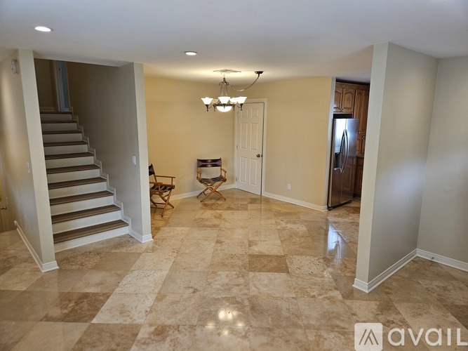 A spacious room with a marble floor and a staircase on the left side.
