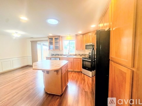 A kitchen with wooden cabinets and a black refrigerator.