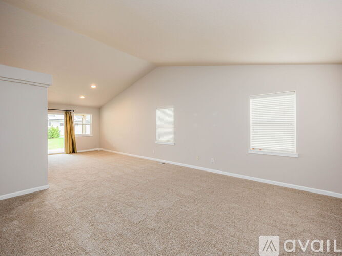 A spacious room with carpeted floor and two windows.