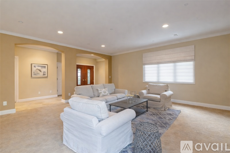 A spacious living room with a white sofa set and a coffee table.