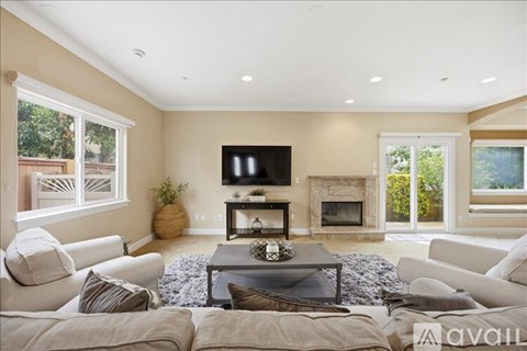 A spacious living room with a white sofa set and a coffee table.