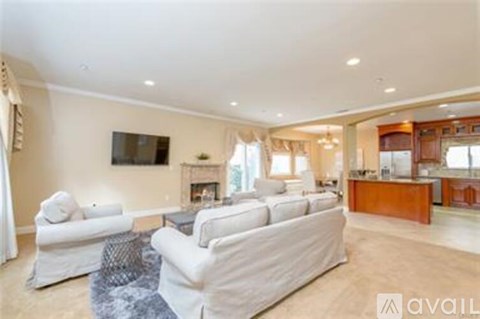 A living room with a white couch and a television mounted on the wall.