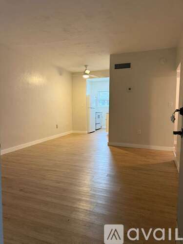 A room with wooden flooring and white walls, with a door on the right side.