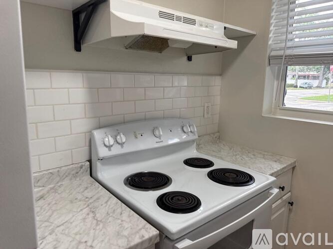 A white stove top oven with four burners is installed in a kitchen.
