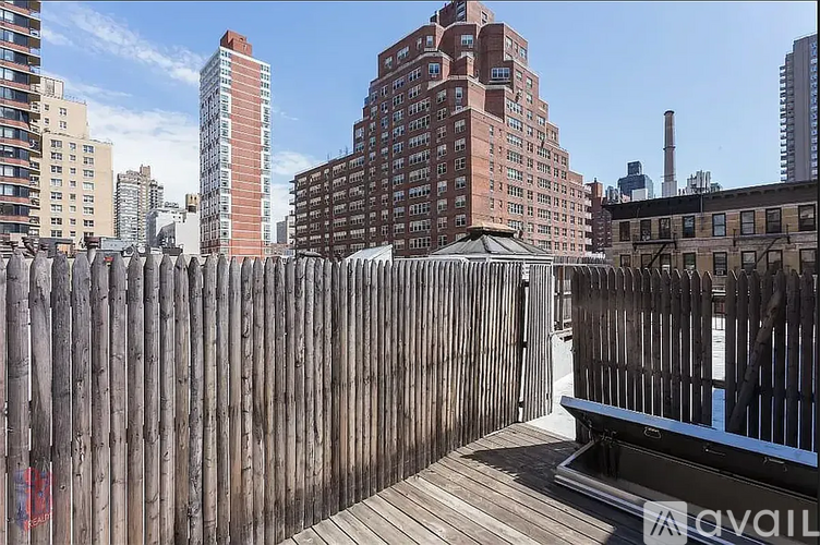 A wooden fence in the foreground with a city skyline in the background.