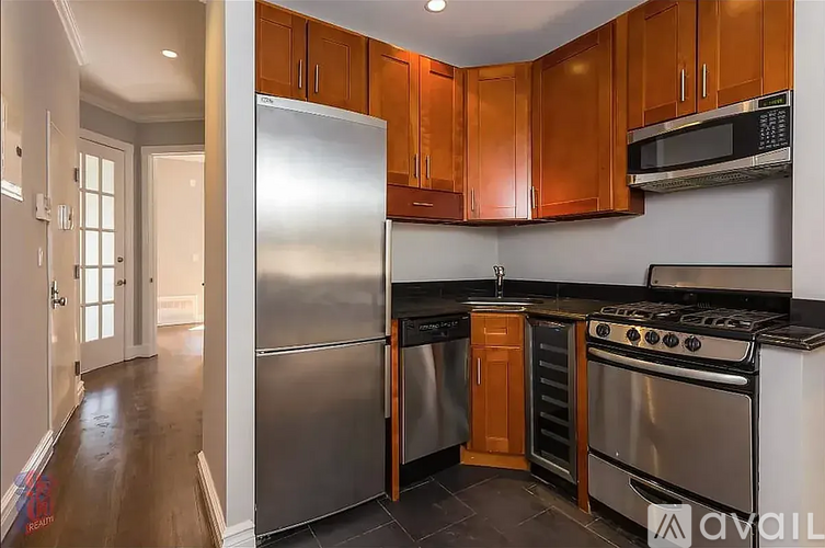 A kitchen with wooden cabinets and a stainless steel refrigerator.
