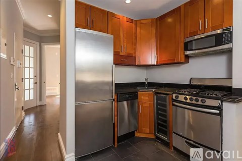 A kitchen with wooden cabinets and a stainless steel refrigerator.