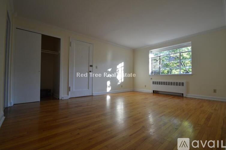 A room with wooden floors and a window showing trees outside.